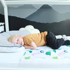 Child sleeping on a bed with a dinosaur-patterned waterproof mattress protector