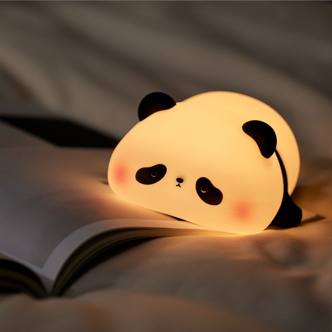 A night light designed to look like a panda, placed on an open book.