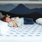 Boy cuddling his toys lying on the lightening bolt waterproof mattress protector.