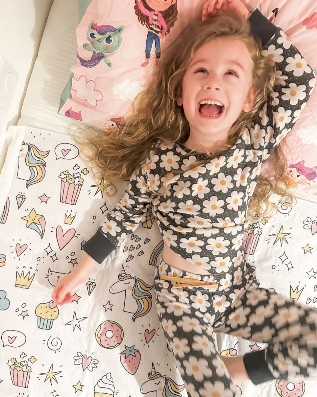 Child in floral pyjamas jumping on a bed with the unicorn design waterproof bed protector