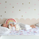 Girl asleep cuddling her lamb on a rainbow toilet training mattress protector.
