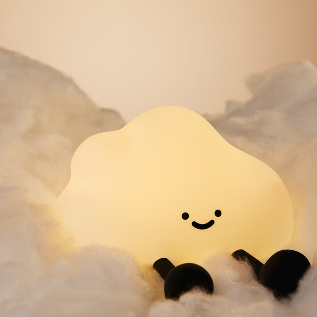 Cute cloud-shaped night light with a smiley face on a soft surface