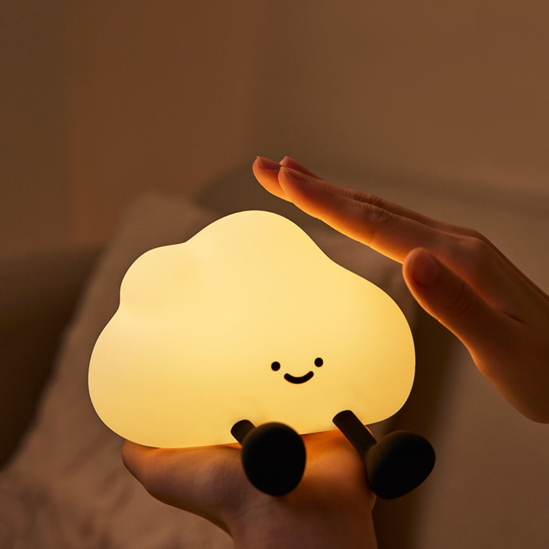 Cute cloud-shaped night light held by a hand with a warm glow.