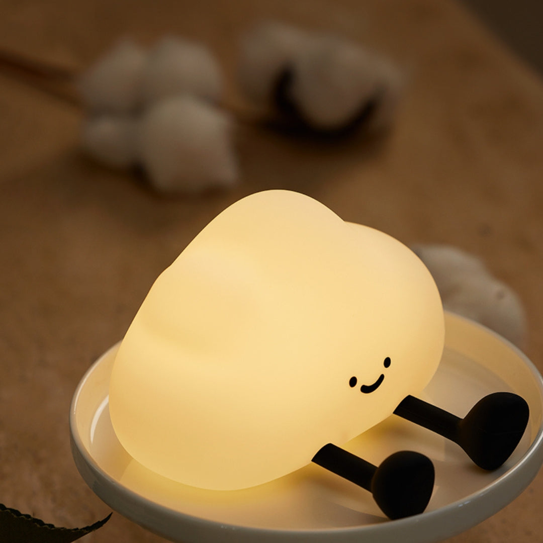 Cute lamp shaped like a cloud with a smiling face on a wooden surface.