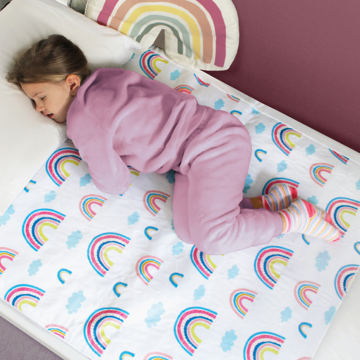 Child sleeping on a bed with the rainbow designed waterproof mattress protector