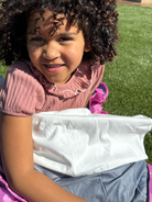 Little girl sat outside in a sleeping bag using her waterproof sleeping bag liner.