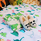 Dinosaur waterproof mattress protector with some dinosaur pyjamas and slippers resting on top.
