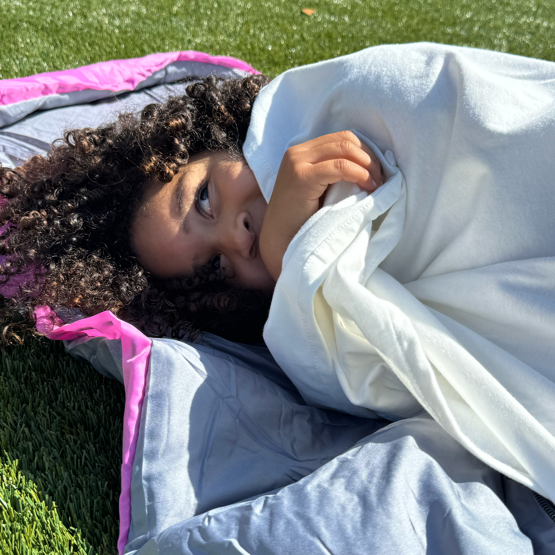 Little girl sleeping outside in a sleeping bag using her waterproof sleeping bag liner.