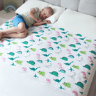 Child sleeping on a bed with a dinosaur-patterned waterproof mattress protector