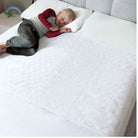 A child lying on a white waterproof mattress protector designed for double beds.