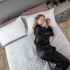 Woman lying on a organic bamboo waterproof mattress protector in a bedroom setting