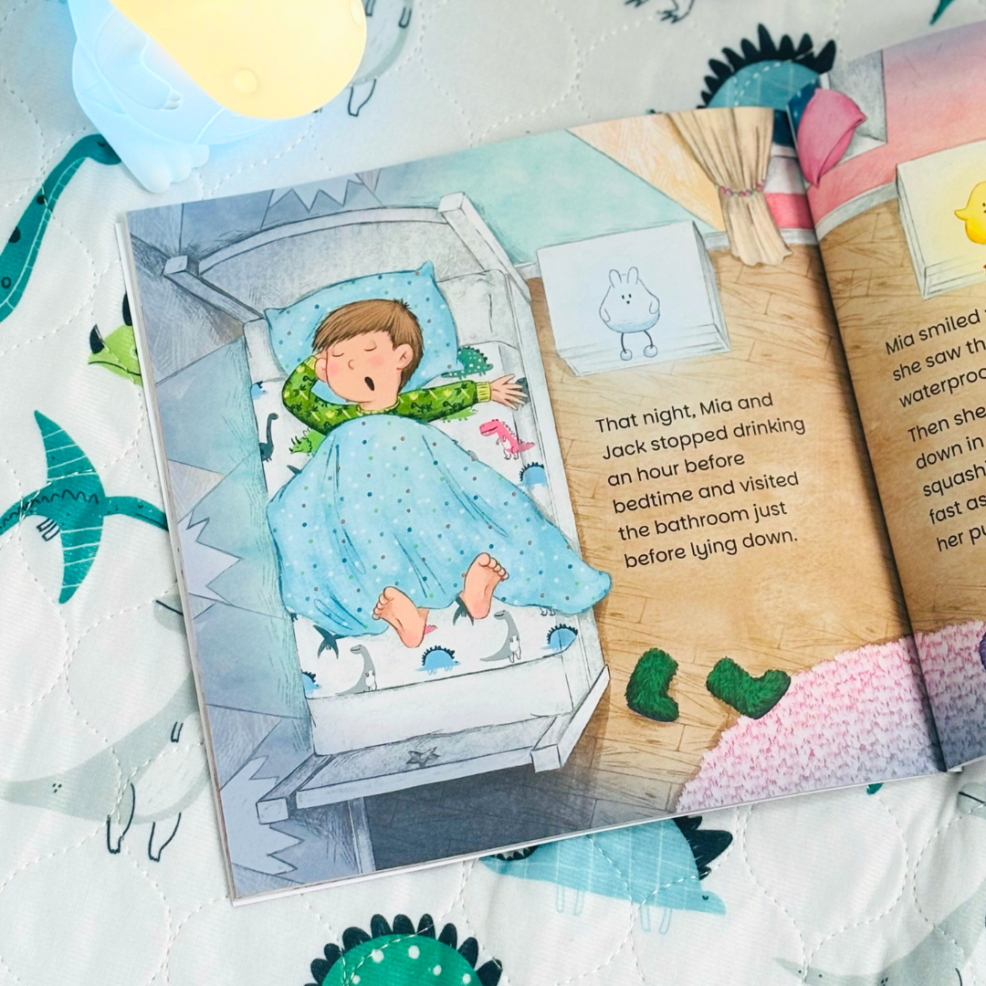 Sample page of the children's book ' Keeping Bed Dry' with illustration of a child sleeping in bed , placed on a dinosaur waterproof mattress protector.