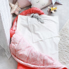 A white waterproof sleeping bag liner for kids displayed on a pink sleeping bag, surrounded by soft toys and a book.