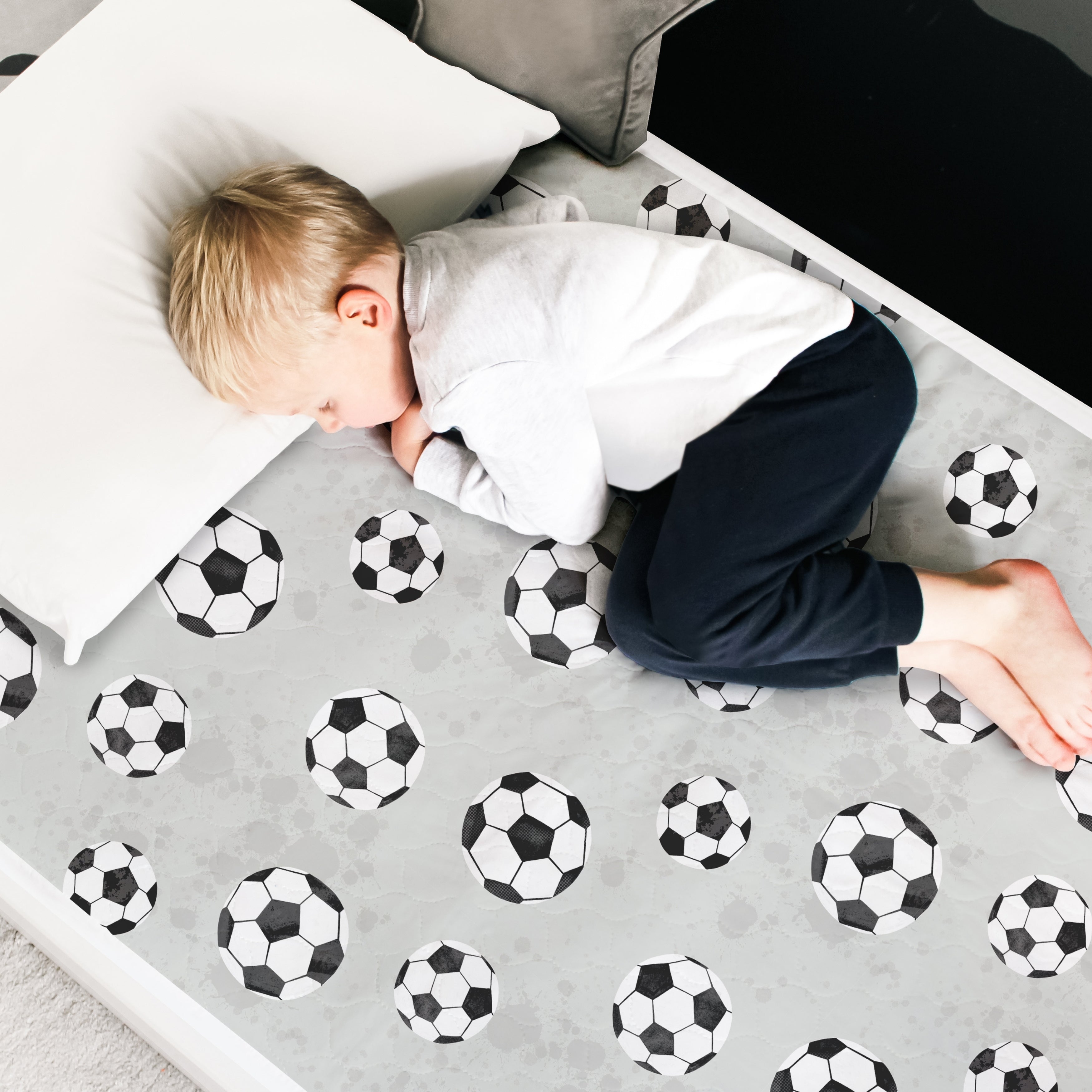 Football themed waterproof mattress protector with a little boy asleep on top.