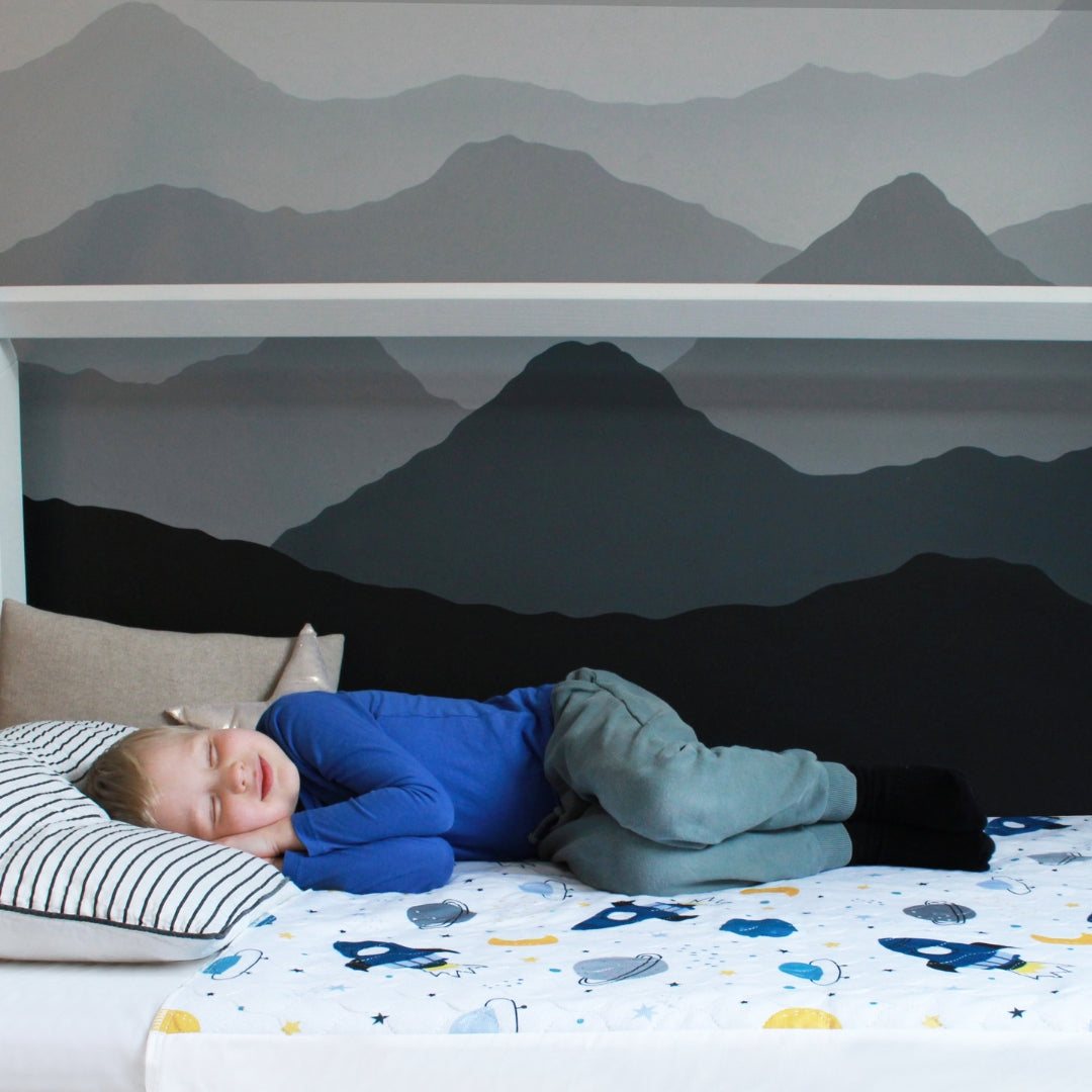 Kid sleeping on space kids waterproof mattress protector