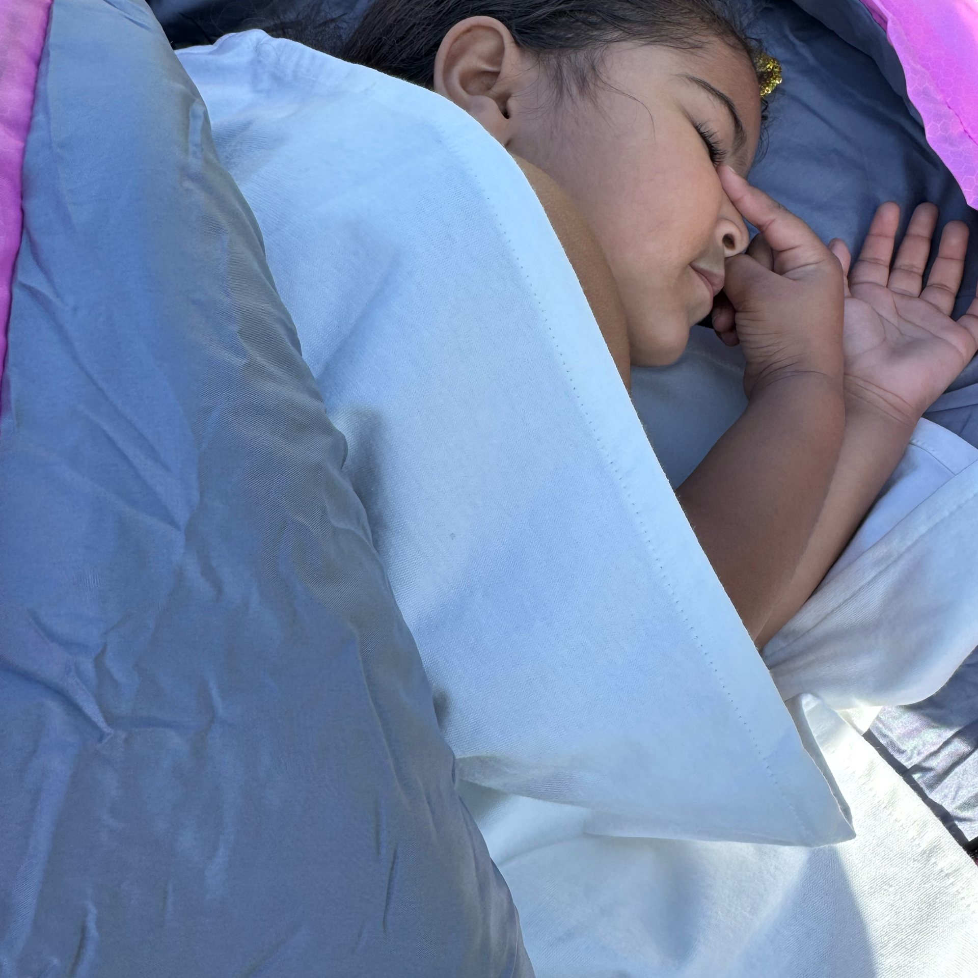 Little girl sleeping outside in a sleeping bag using her waterproof sleeping bag liner.