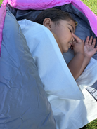 Little girl sleeping outside in a sleeping bag using her waterproof sleeping bag liner.