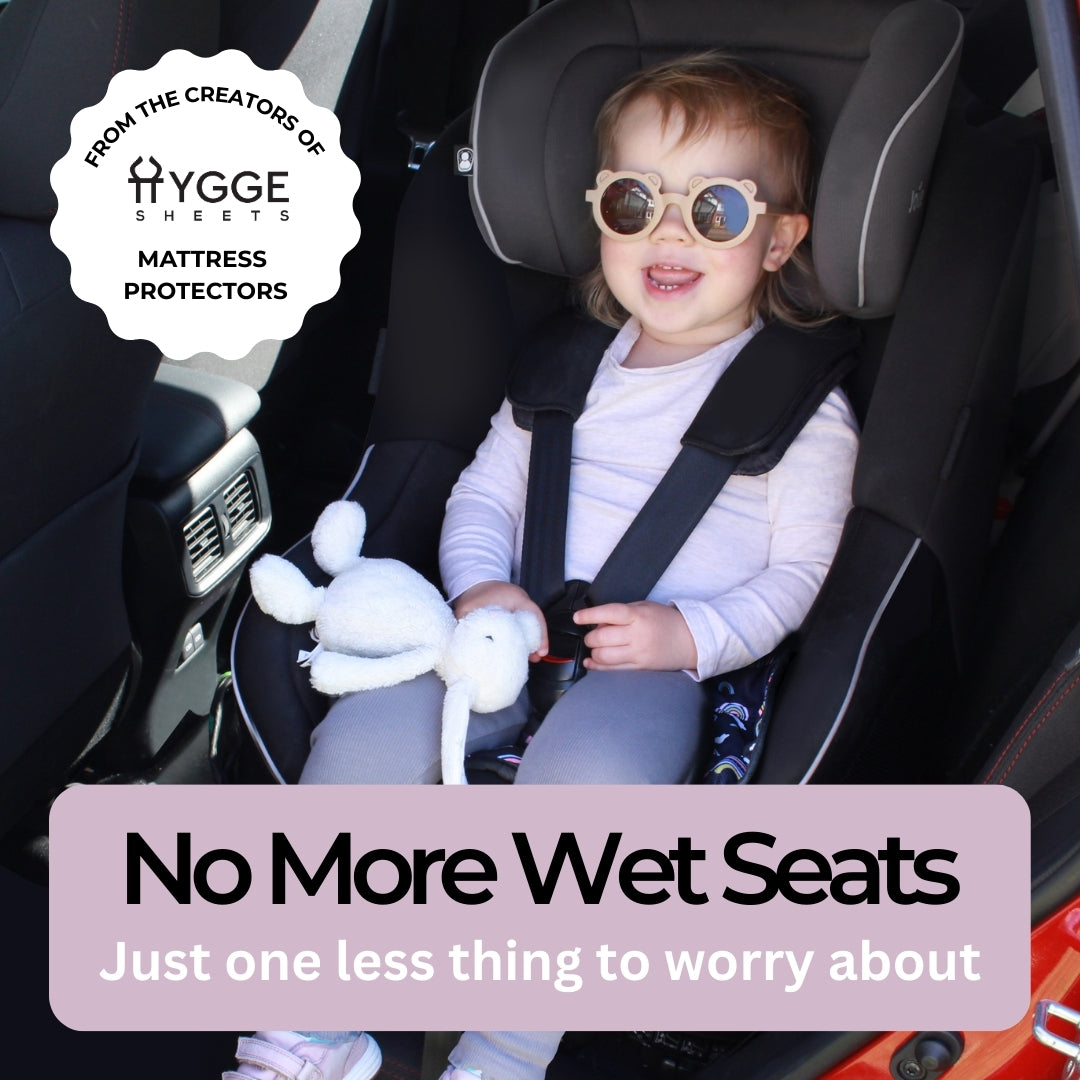 Child in a car seat with a rainbow protector and text saying 'no more wet seats'