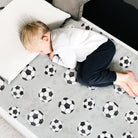 Football themed waterproof mattress protector with a little boy asleep on top.