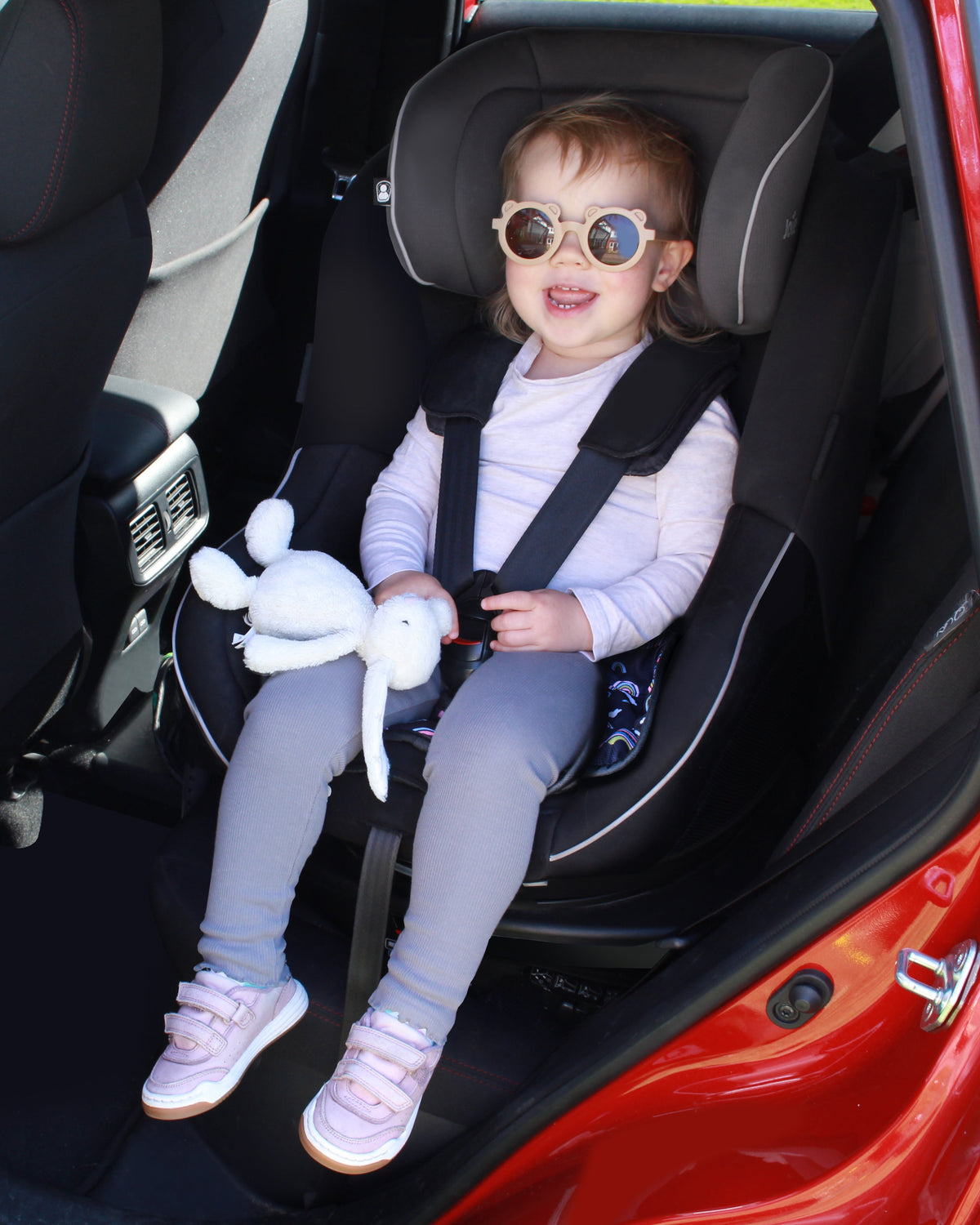 Child in a car seat using a Hygge rainbow print car seat protector